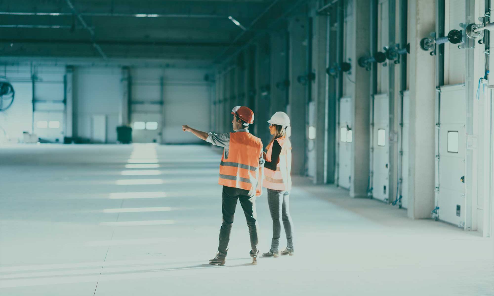 Two people in an industrial setting with a building
