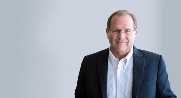 A man in a suit and tie smiling for the camera.