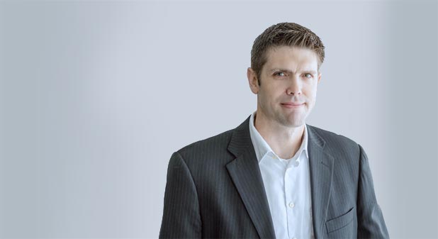 A man in a suit and tie standing next to a wall.